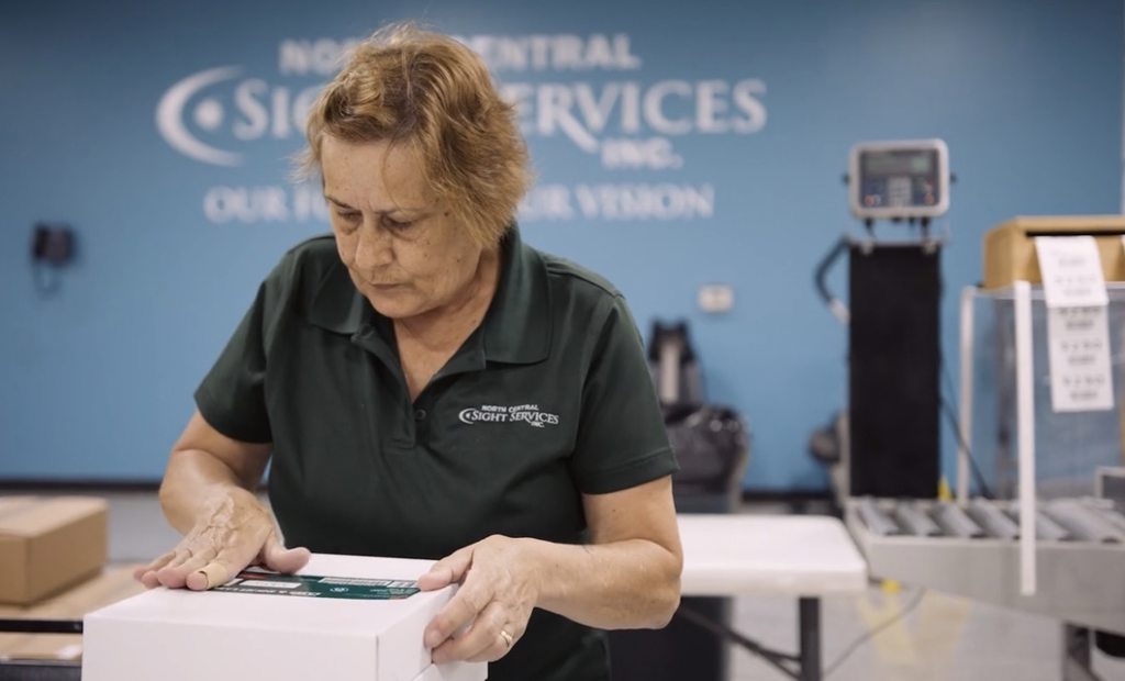 Employee in green shirt placing a label on a box