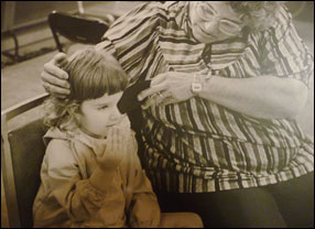 A black and white photo of an adult covering a child's eye during a vision screening.