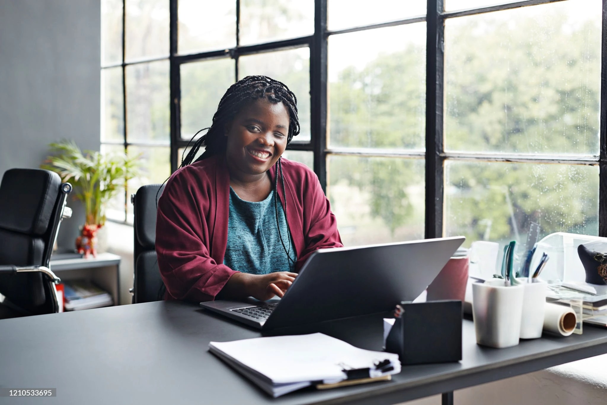A woman sits at her computer smiling at the camera